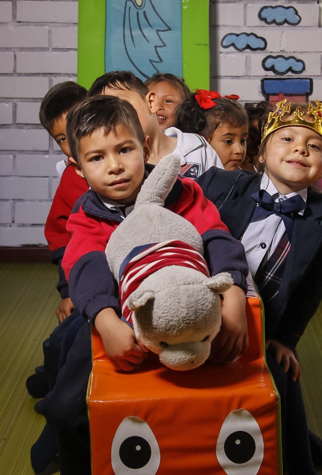 Grupo de estudiantes de preescolar sonriendo juntos con un peluche